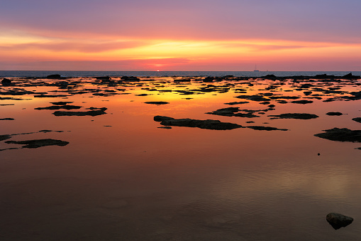 Sunset Reflected on the Sea as in a Mirror with Rocks Emerging on the Surface of the Water.