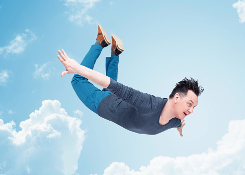 Happy man in casual clothes, flying in the sky, around a cloud. The concept of travel