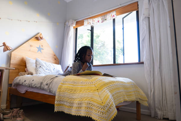 istock Girl lying on her bed reading a story book 1555134694