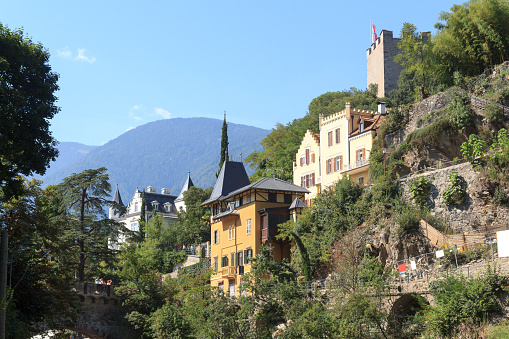 Merano, Italy - September 10, 2021: Panorama view of Powder Tower above Merano, villa mansions and mountains in South Tyrol, Italy