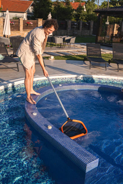 istock Men cleaning the swimming pool with a net 1555181780