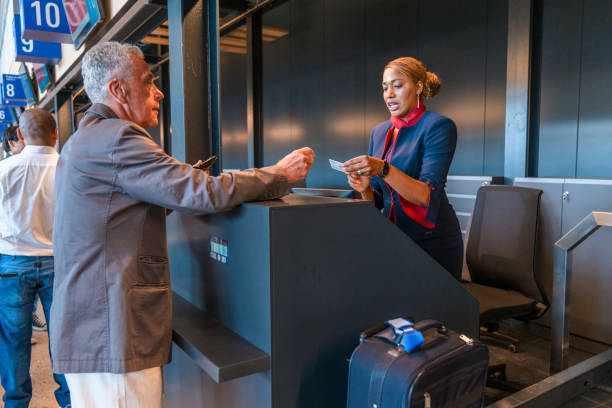 Mid Adult Hispanic Airline Stewardess At The Airport Check In Counter Mid adult Hispanic airline stewardess sitting at a check in counter at the airport. Checking boarding passes. check in person stock pictures, royalty-free photos & images