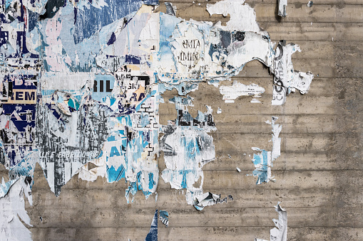 Concrete wall with colorful ripped bill posters. Grunge background