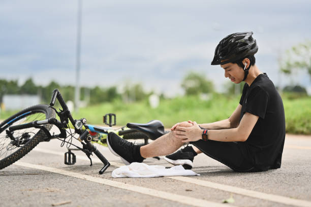 istock Bicycle accident. Young cyclist having an accident, falling down from bicycle and injured his knee. 1555233544