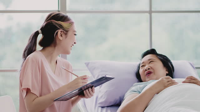 An senior woman laughs beside a friendly young care assistant