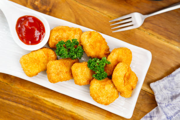 istock Appetizing fried chicken nuggets on a white plate in a restaurant. Top view. 1555302364
