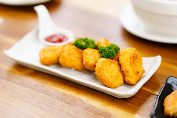 istock Delicious fried chicken nuggets on a white plate in a restaurant. Selective focus. 1555302919