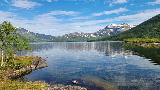 view of Brostadbotn, Norge, featuring a large lake with a small island situated near the majestic mountains