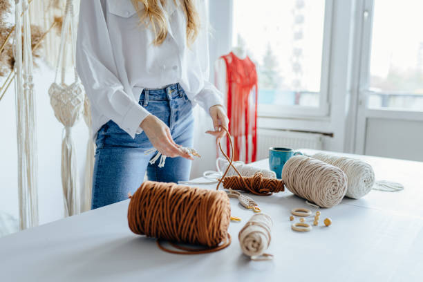 istock Hand of unrecognizable woman when she is making macrame. Natural cotton threads. Handmade macrame in work process. 1555336972