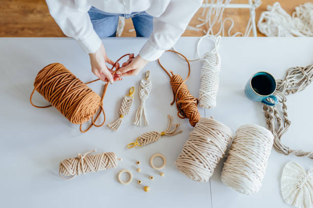 istock Creative hobby handmade macrame for home decoration. Girl weaves macrame. Flat lay, top view. 1555342661