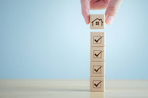 istock Checklist while buying your house. Hand holding house from stack that check mark are completed for home buying checklist. Refinance, home loan, tax, mortgage, buy, rent, property investment concept. 1555346077