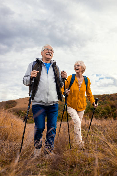 Active senior couple with backpacks hiking together in nature on autumn day. stock photo