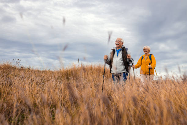 Active senior couple with backpacks hiking together in nature on autumn day. stock photo
