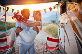 A young man is holding his bride in the arms at the camp in the nature. Relationship, honeymoon, camping, nature