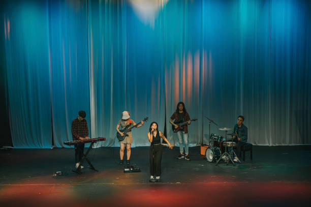 istock Young Asian Multiracial group female lead singer live band performance on stage 1555390425