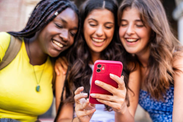 istock Three happy friends watching a smart phone mobile outdoors - Millennials women using cellphone on city street - Technology, social, friendship and youth concept 1555391516
