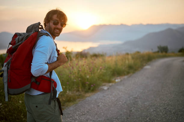 istock Hiking. Young man with backpacks at  evening 1555399413