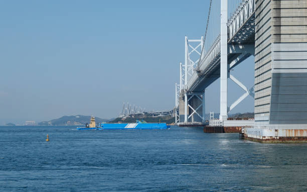 "Pusher Barge", a working boat that crosses the Seto Ohashi Bridge (Sakaide City, Kagawa Prefecture) On a sunny day in March 2023, at the Seto Ohashi Memorial Park at the northern end of the Bannoshu industrial area in Sakaide City, Kagawa Prefecture, a working ship "Pusher Barge" crosses the Seto Ohashi Bridge. 押す stock pictures, royalty-free photos & images