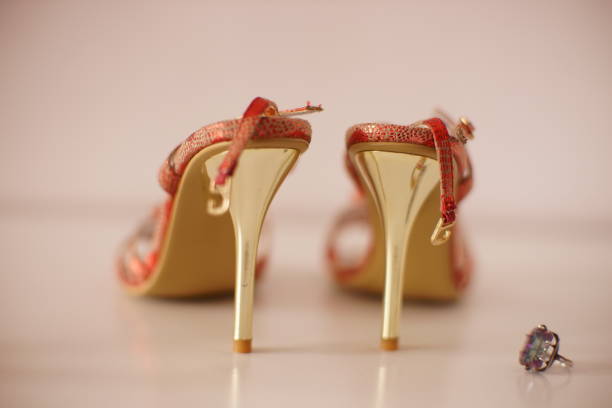 istock Red summer sandals on thin gold heels with ring mystic topaz on a white table. 1555399954