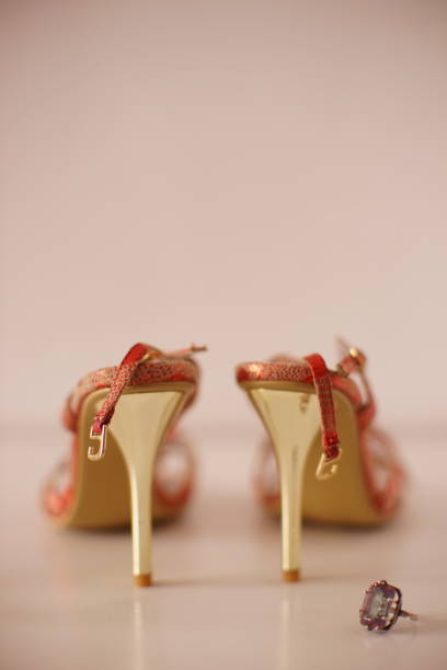 istock Red summer sandals on thin gold heels with ring mystic topaz on a white table. 1555400470