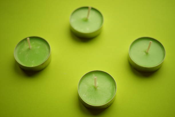 Four low new green candles on lime table. Top view.