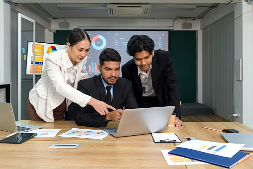 Group of business people in suit making presentation document in the meeting room. Business executives team meeting at night in modern office with laptop computer, tablet and coffee cup on the table.