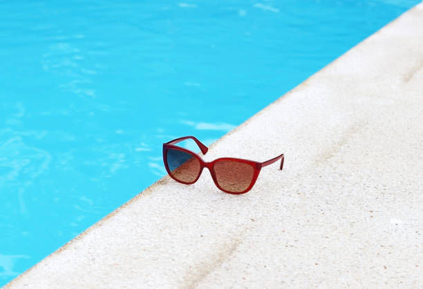 istock Red glasses at the edge of a pool. Space for text. 1555413093
