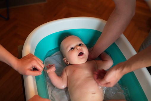 Newborn baby boy being bathed by his parents