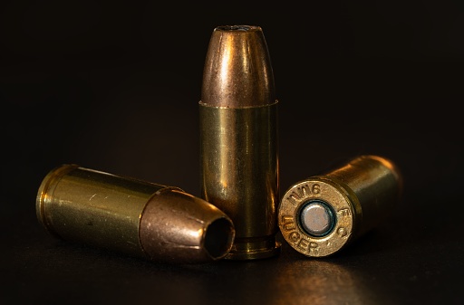 A close-up shot of 9mm bullets on a dark background.