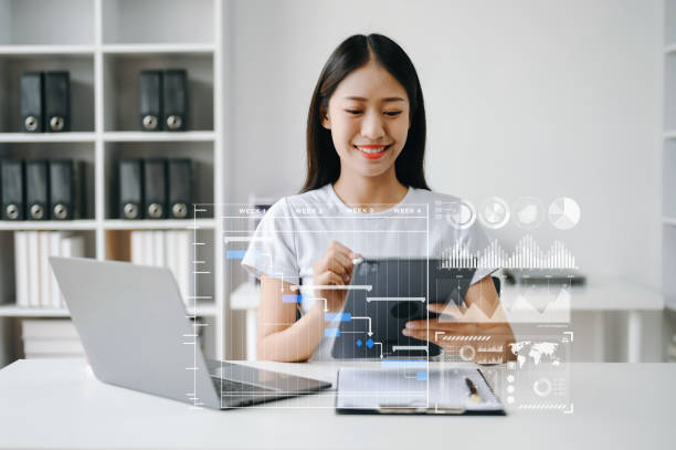 istock Asian Businesswoman hand Project manager working and update tasks and Gantt chart scheduling virtual diagram.with smart phone, tablet and laptop in office. 1555433165