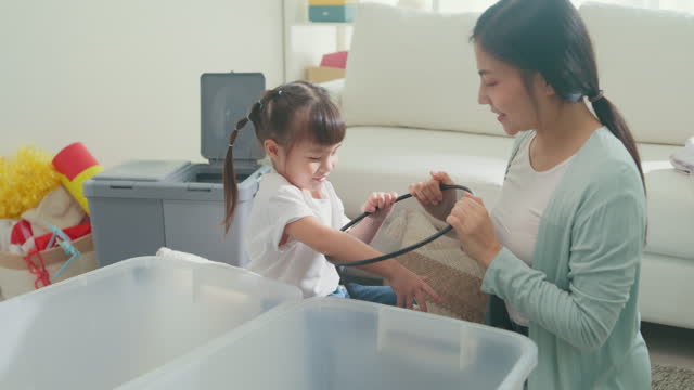 Young Asian family mom teaching kid how to recycle help girl aware environmental importance in living room at home. Family happy moment concept.