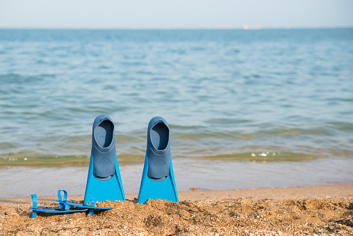 beach, flippers for swimming on a sandy beach, blue sea in the background, traveland holiday time