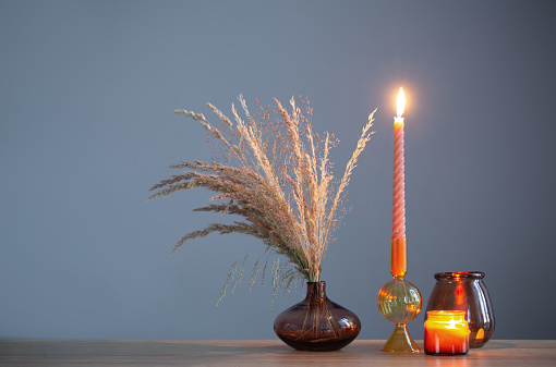 dried flowers and burning candles on background dark wall