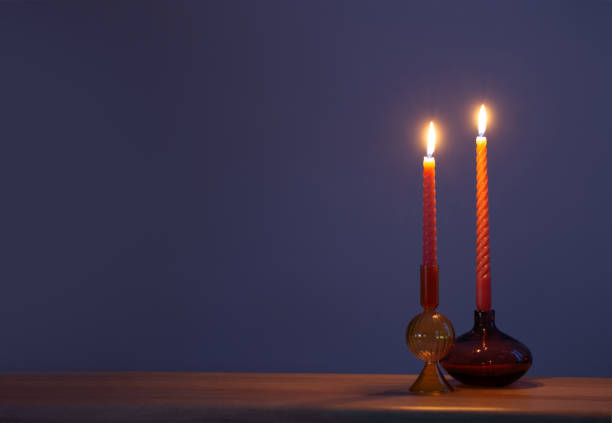 burning candles in glass candlesticks on dark blue background