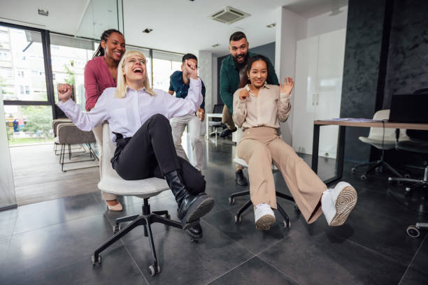 istock Group of professional people racing with the chairs while on a break in the modern office 1555456942