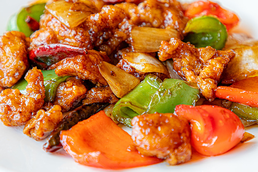 Chop Suey is a quick Chinese American stir-fry with chicken and mixed vegetables in a thick brown sauce close-up in a plate on the table. Horizontal top view from above