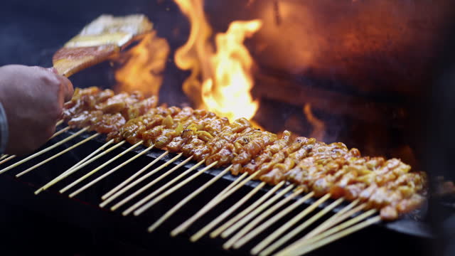 The popular Malaysian street food, Satay, is cooked on a flaming barbecue grill.