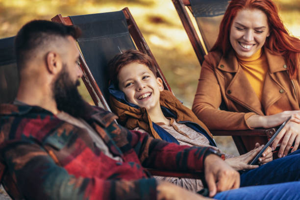 istock Young family enjoying time in a outdoor cafe using digital tablet. 1555463108