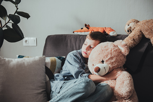 Sad little boy hugs cute brown teddy bear. The concept of loneliness and sadness, depression