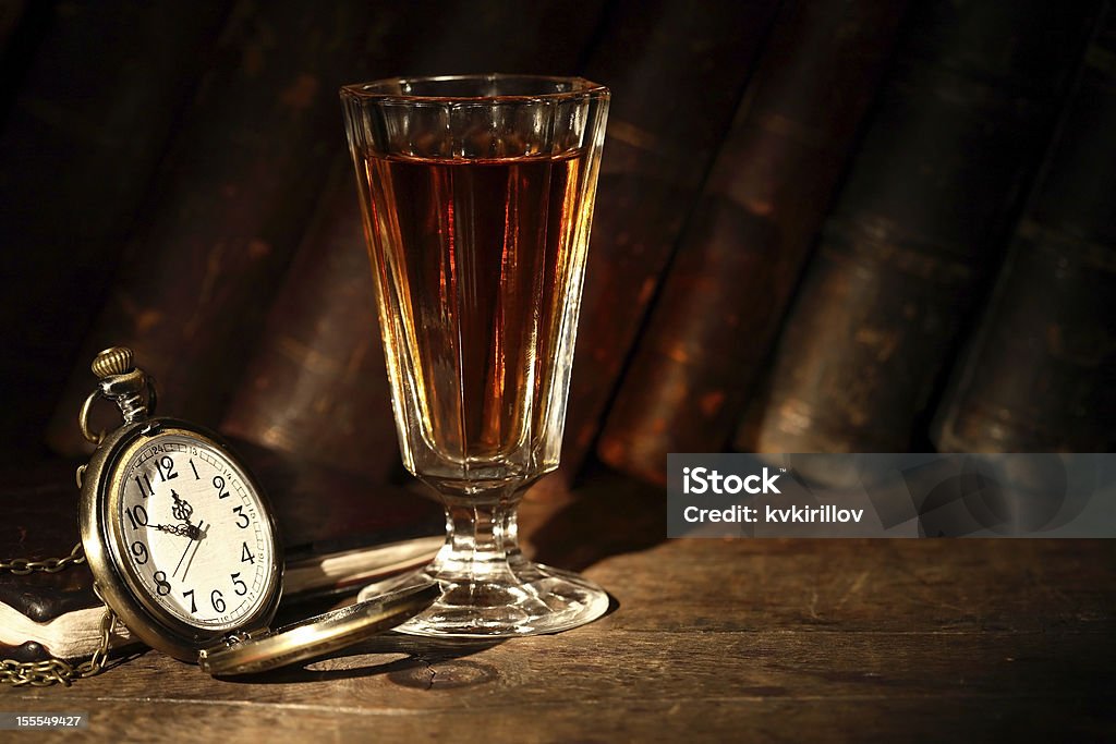 Some Drink For Good Night Vintage small wineglass with alcohol near open pocket watch on background with old books Alcohol - Drink Stock Photo