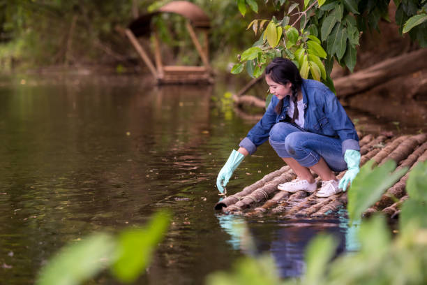istock Asian student biology taking and testing sample of natural river water. Experts science women keep water for research analysis in the laboratory. 1555500417