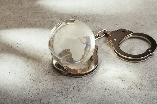Crystal globe in handcuffs. Global crime concept