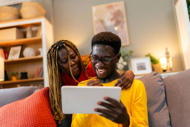 istock Happy young couple using a digital tablet together while relaxing on a couch at home 1555532412