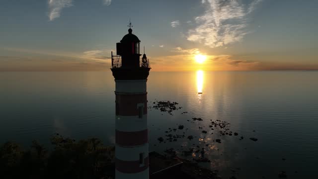 Aerial view of the lighthouse at sunset. Drone view of the sea lighthouse on the bay