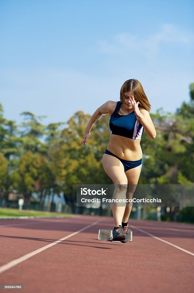 Young woman running Young woman during a running race in a summer day at the athletic field. Adult Stock Photo