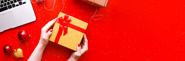 istock Banner Flat lay hands holding a gift with a red bow. Christmas 1555562038