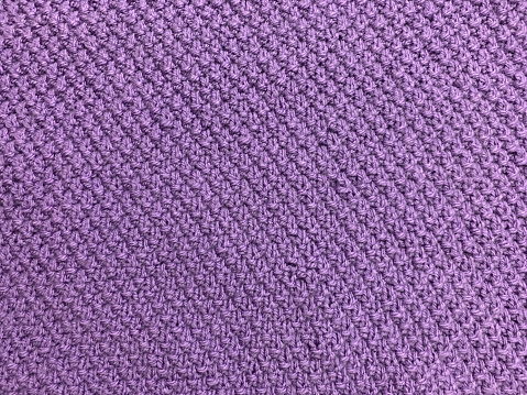 Woven purpule wool fabric texture. Hand knitted textile canvas background. Patchwork carpet backdrop. Factory material threads. Abstract design. Close-up, mockup, top view