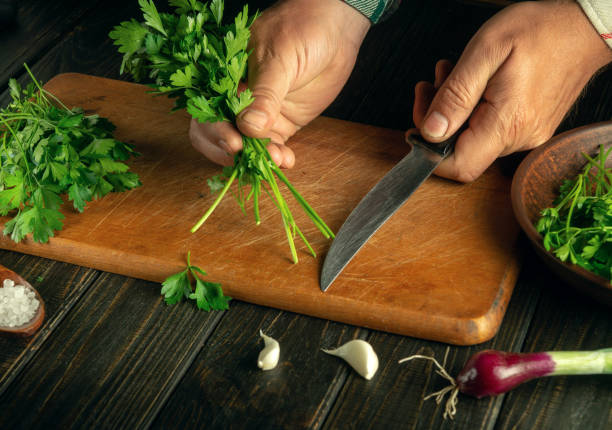 istock A man getting ready to cut fresh parsley for a vegetable salad on a cutting board. Cooking vegetarian food at home. The idea of a vegetable diet for a set of vitamins. 1555578390