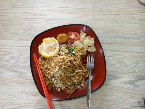 istock Typical Asian Fried Noodles with egg topping, tomatoes, nuggets and others 1555604976