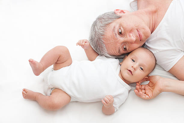 Grandmother and grandson lying on the ground, baby is looking at the camera